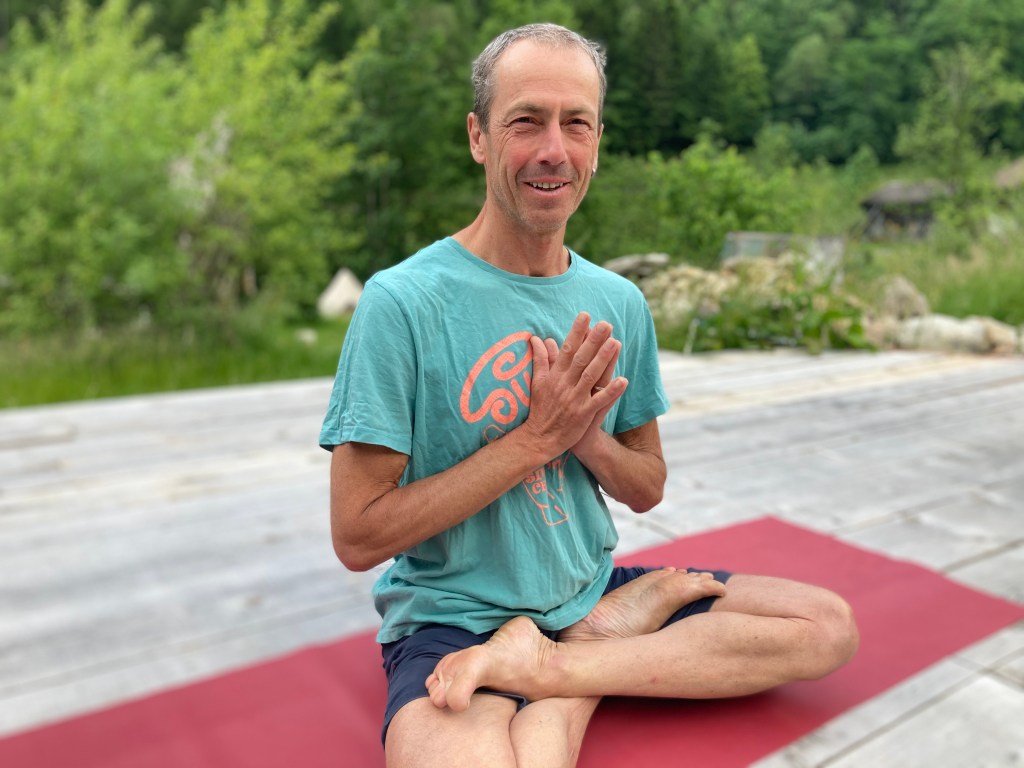 Markus Böhme im Schneidersitz vor grüner Wiese